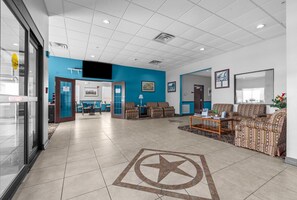 Relax in our spacious lobby, featuring a seating area with sofas and armchairs, a reception desk, and a flat-screen TV.