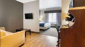 A hotel room with a bed, a desk, a chair, a TV, and a window with curtains. - Best Western Plus Olathe Hotel (Olathe)