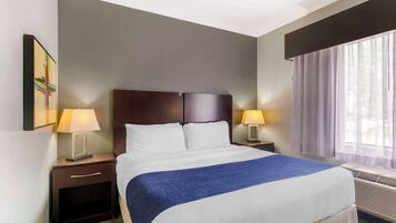 A hotel room with a large bed, two bedside tables with lamps, a window with curtains, and a wall-mounted TV.