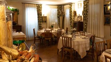 A dining area with round tables, chairs, and a central decorative plant.