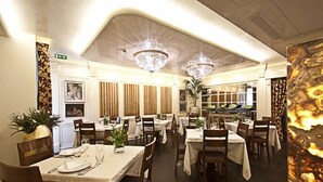 A restaurant with multiple tables, wooden chairs, and chandeliers. - Locanda Al Sole (Castello di Godego)