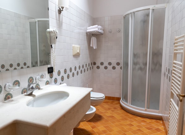 A bathroom with a white sink, toilet, and a glass-enclosed shower.