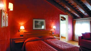 Ein Zimmer mit Holzboden, roten Wänden, einem Bett mit roter Bettwäsche, zwei Nachttischlampen, einem gerahmten Bild an der Wand und einem Fenster mit Vorhängen.
