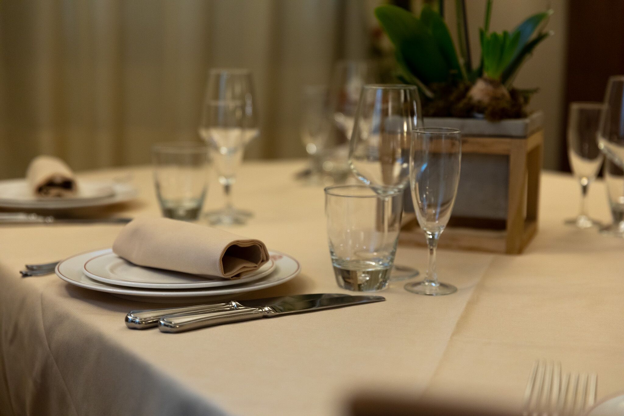 Una mesa preparada para comer, con platos, cubiertos y vasos.