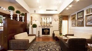 A spacious living room with a fireplace, wicker furniture, and a patterned rug. - Locanda Al Sole (Castello di Godego)