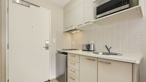 Una cocina moderna con armarios blancos, un lavamanos de acero inoxidable y un microondas integrado.