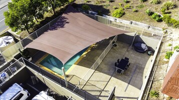 An outdoor patio with a covered seating area, a pool, and a fenced garden.