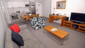 Una sala de estar moderna con sofá, reposapiés, mesa de centro, televisor y escritorio con silla.