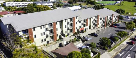 A multi-story hotel with a flat roof, parking lot, and a view of the surrounding neighborhood.