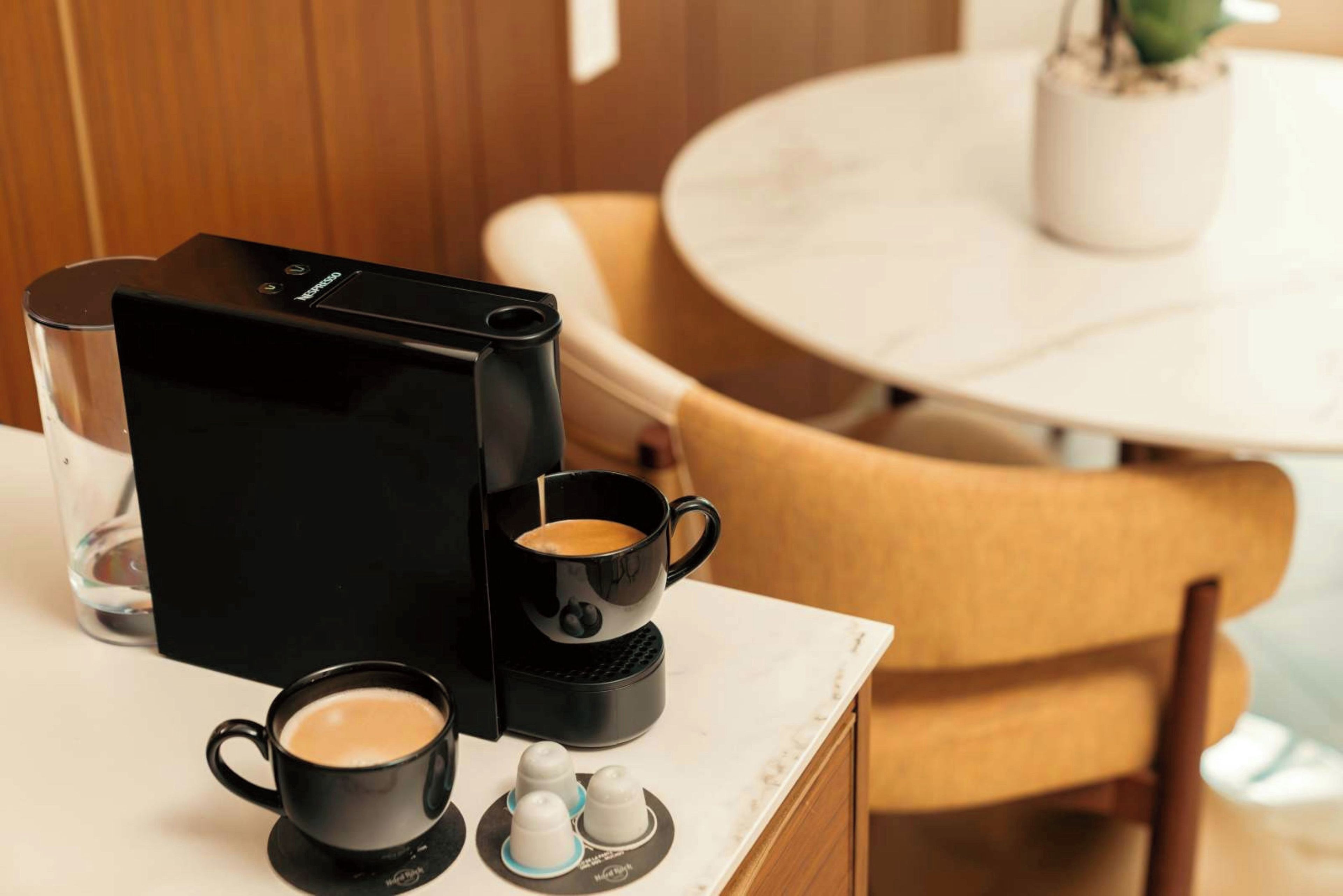 Una cafetera, dos tazas y una jarra de agua sobre una mesa.