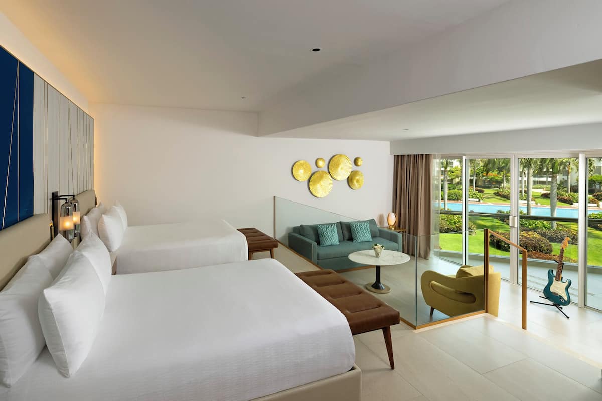 Ein modernes Hotelzimmer mit zwei Betten, einer Couch, einem kleinen Tisch und einem Balkon mit Blick auf einen Pool.