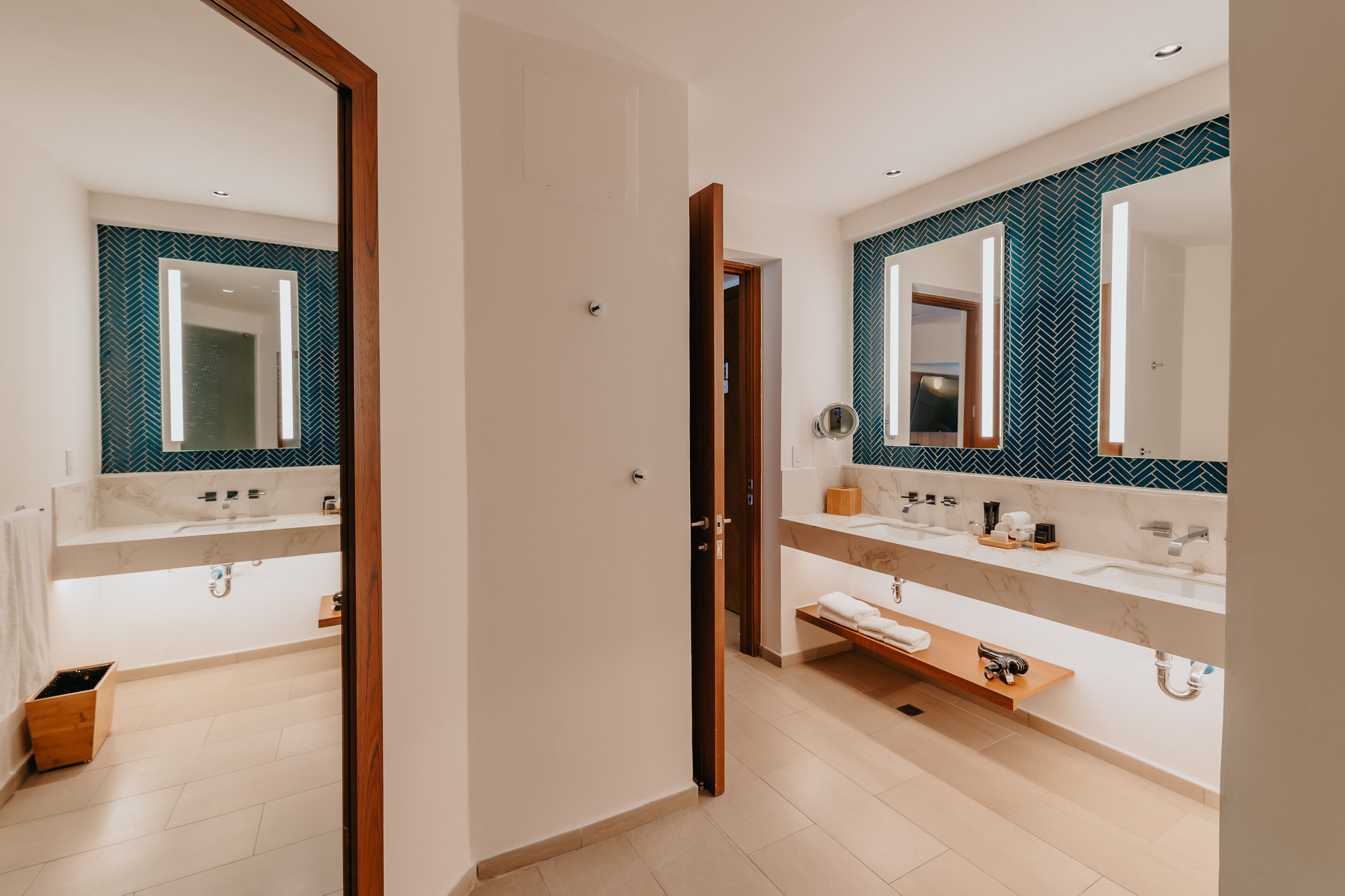 Un bagno moderno con due lavabi, uno specchio e una doccia.