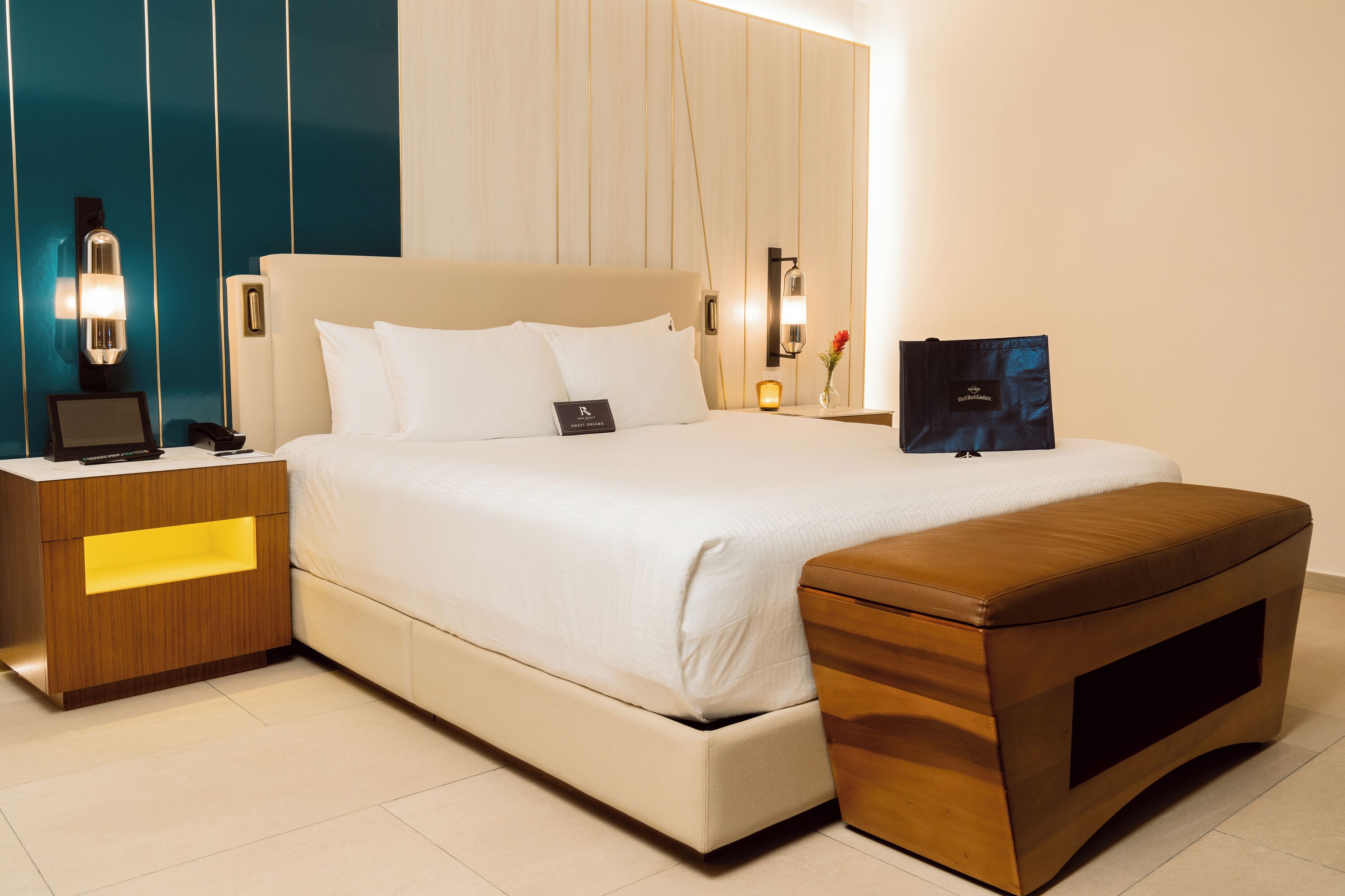 Una habitación de hotel moderna con una cama grande, mesitas de noche y una mesilla.