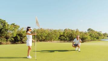Golfers enjoy a serene round on the well-manicured fairway, surrounded by lush trees and shrubbery.