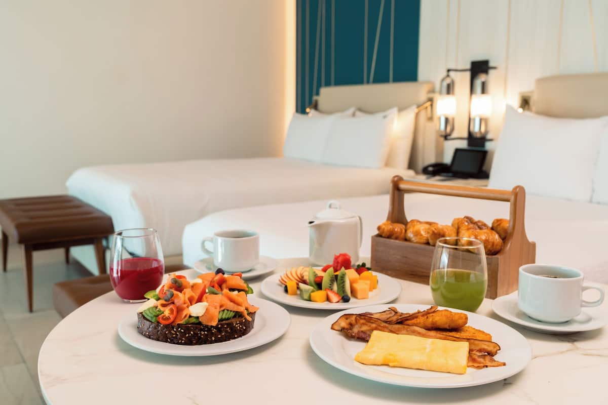 Ein Frühstücksbuffet mit verschiedenen Speisen, ein Bett und ein Nachttisch mit Lampe.