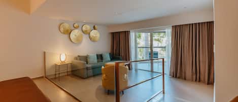 Een ruime woonkamer met een bank, fauteuils, een salontafel en een glazen scheiding.