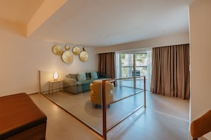 A spacious living area with a sofa, armchairs, a coffee table, and a glass partition.