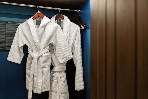 Two white robes hanging on a rack in a room with dark blue walls. - Hard Rock Hotel & Casino Punta Cana an All-Inclusive Resort (Punta Cana)