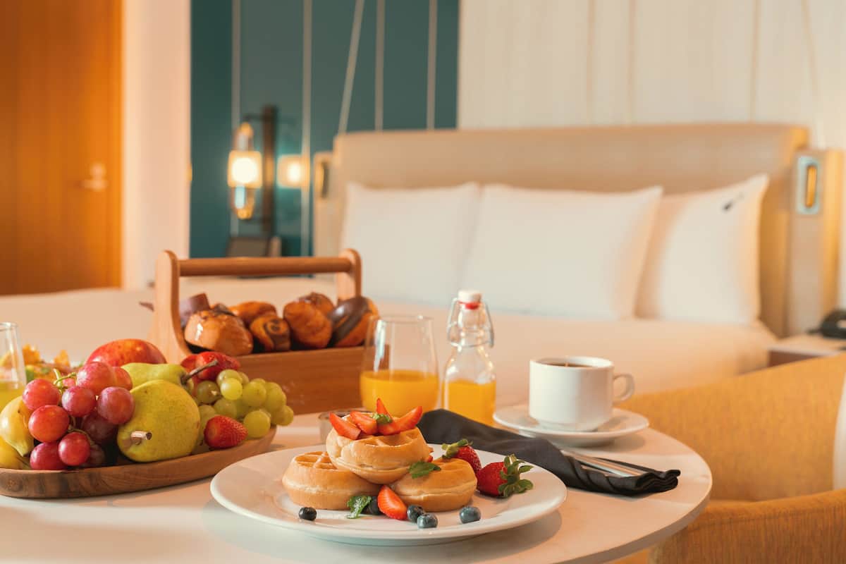 Ein Frühstückstisch mit Früchten, Waffeln und Kaffee in einem Hotelzimmer.