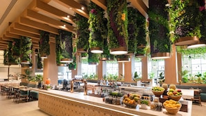 A modern hotel lobby with a long reception counter, hanging plants, and a variety of fruits and snacks. - Hard Rock Hotel & Casino Punta Cana an All-Inclusive Resort (Punta Cana)