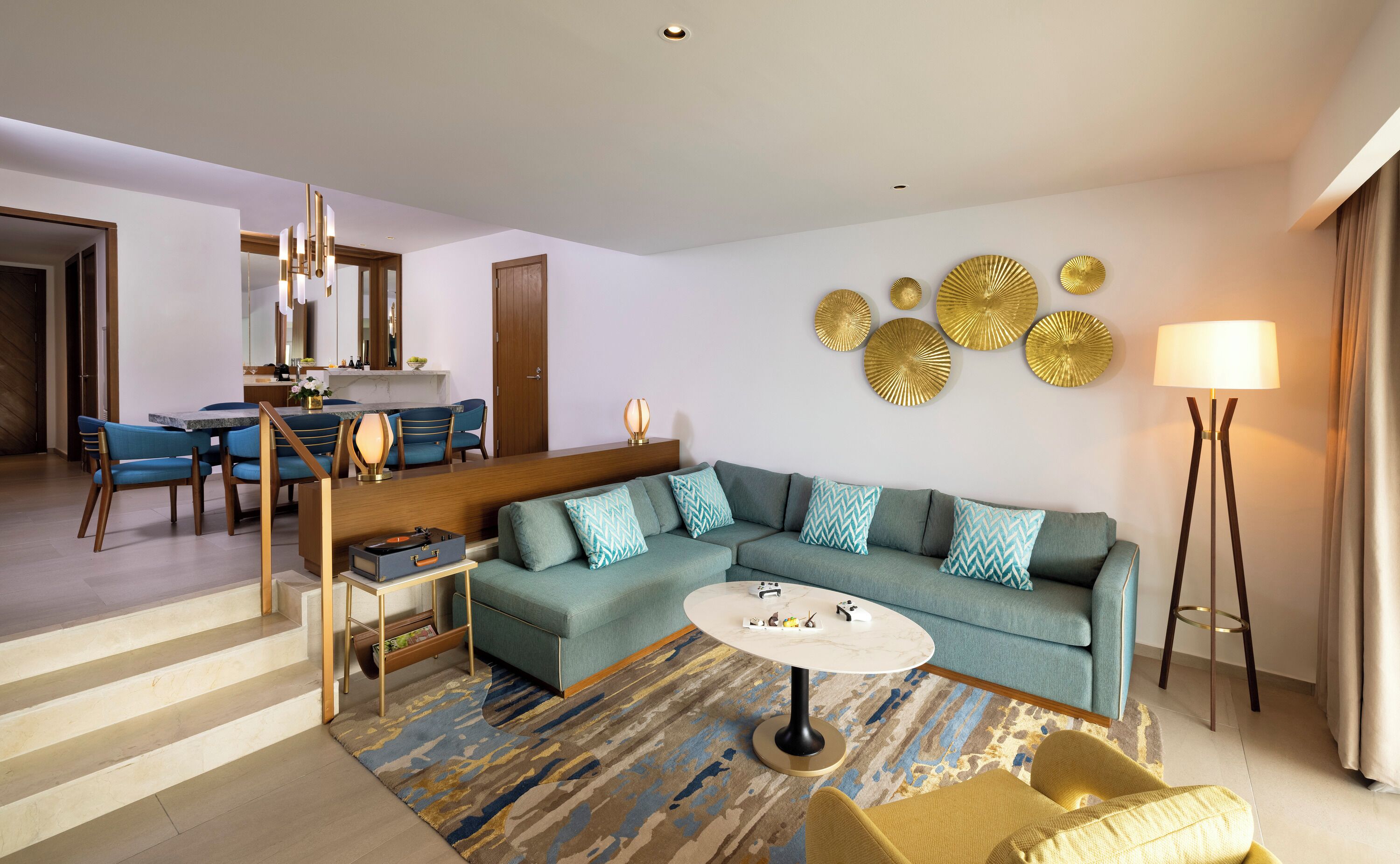 A modern living room with a sectional sofa, a round coffee table, and a dining area with a table and chairs.