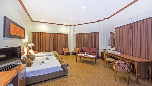 Ein Hotelzimmer mit Bett, Schreibtisch, Sofa und Fernseher.
