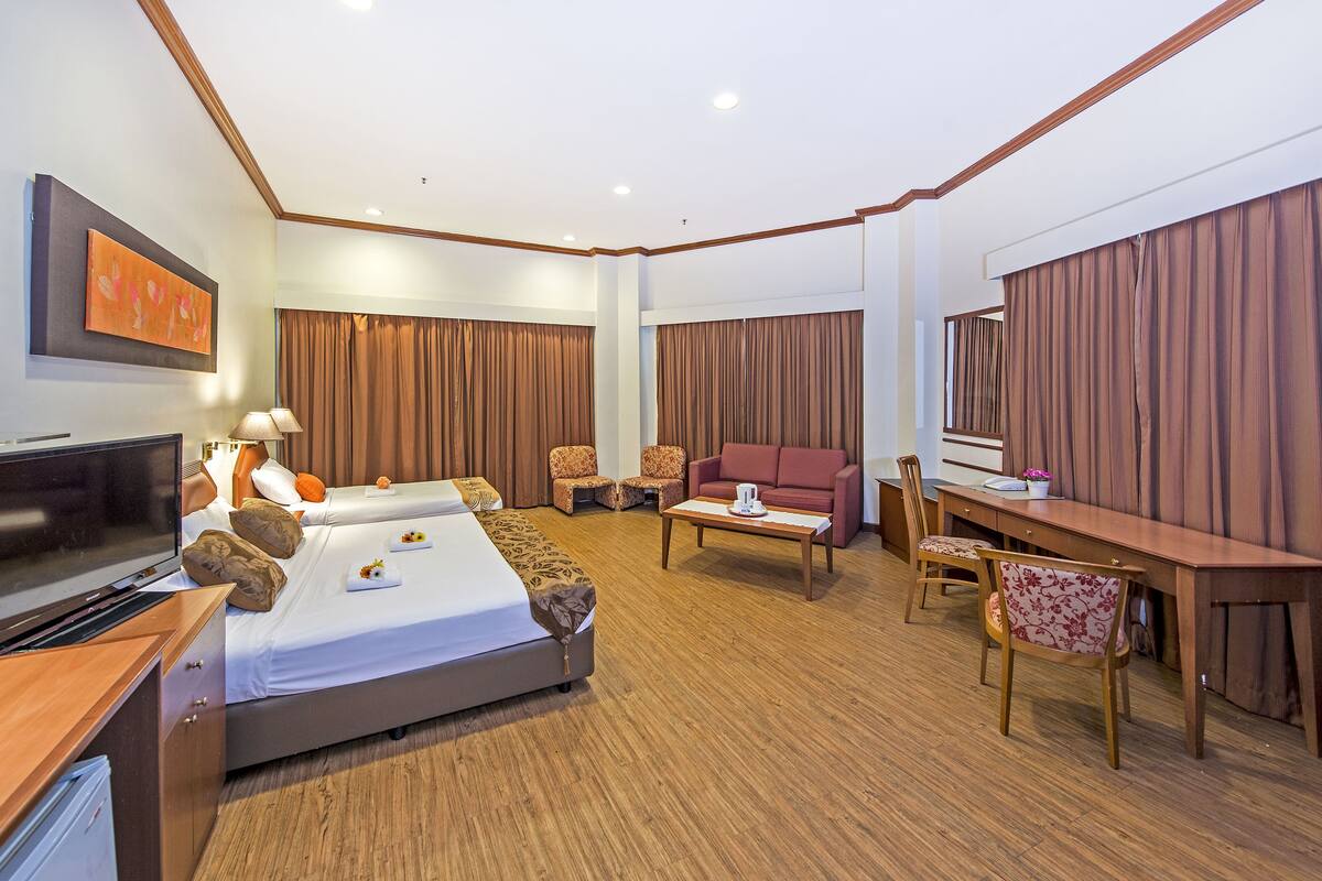 Une chambre d’hôtel avec un lit, un bureau, un canapé et une télévision.