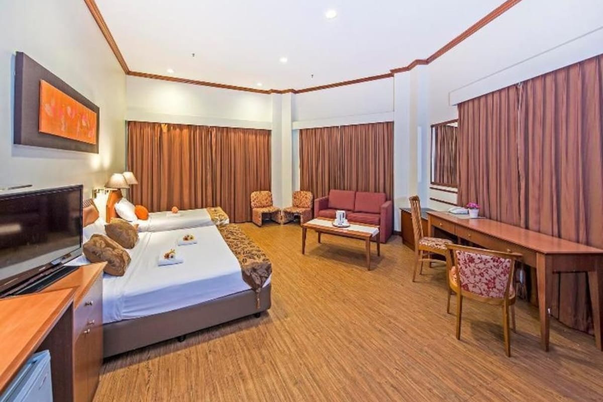 Una habitación de hotel con cama, escritorio, sofá y televisión.