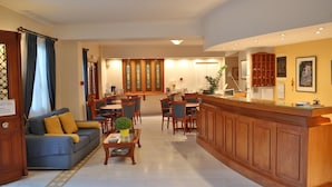 Un vestíbulo de hotel con una recepción, zona de estar y un sofá.