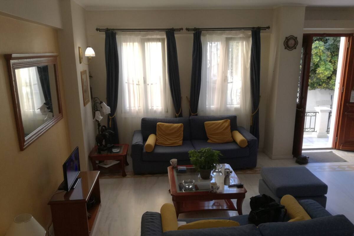 A living room with a sofa, a coffee table, a TV, and a door leading to an outdoor area.