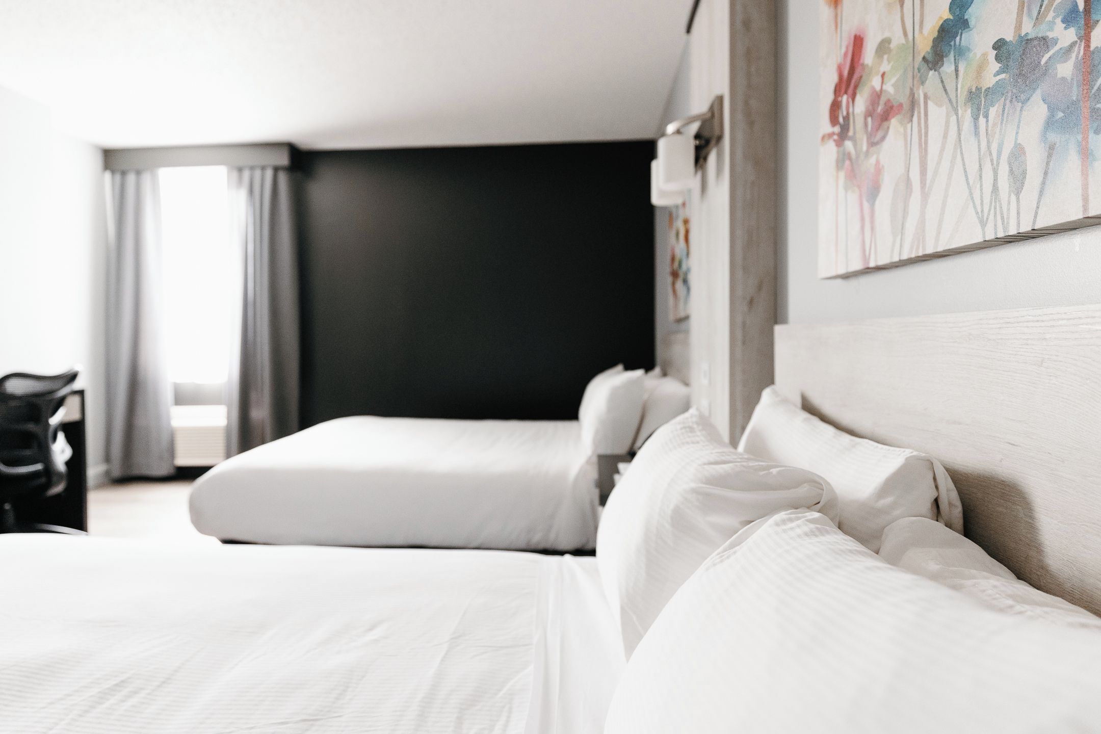A hotel room with two beds, a desk, and a chair.