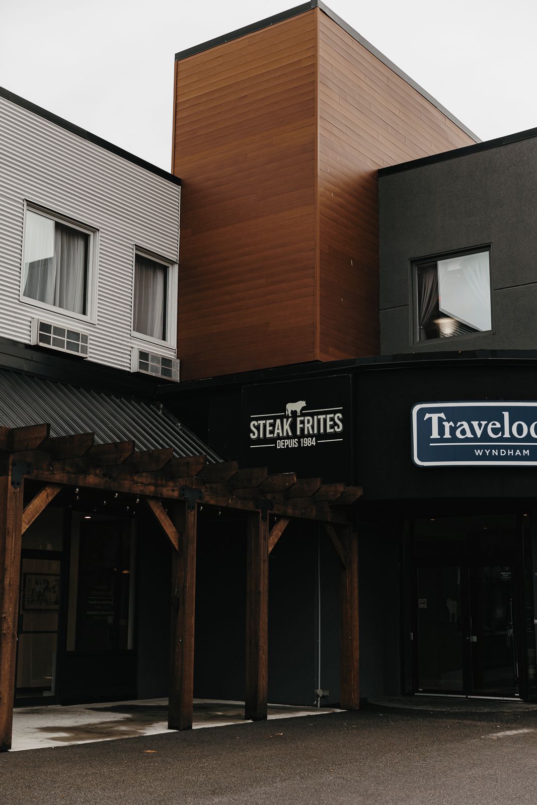 Een gebouw met een bord waarop 'Steak Frites' en 'Travelog Wyndham' staat, wat een restaurant en hotel aanduidt.