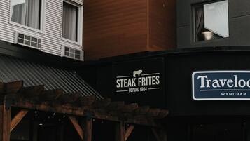 Een gebouw met een bord waarop 'Steak Frites' en 'Travelog Wyndham' staat, wat een restaurant en hotel aanduidt.