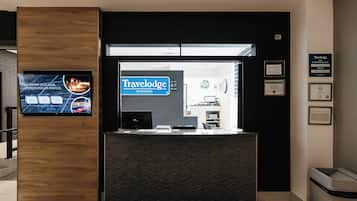 Una recepción con un cartel de Travelodge Wyndham, una pantalla digital mostrando atracciones locales y certificados enmarcados en la pared.