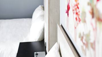 Habitación de hotel con una cama, una mesita de noche con teléfono y una lámpara de pared.