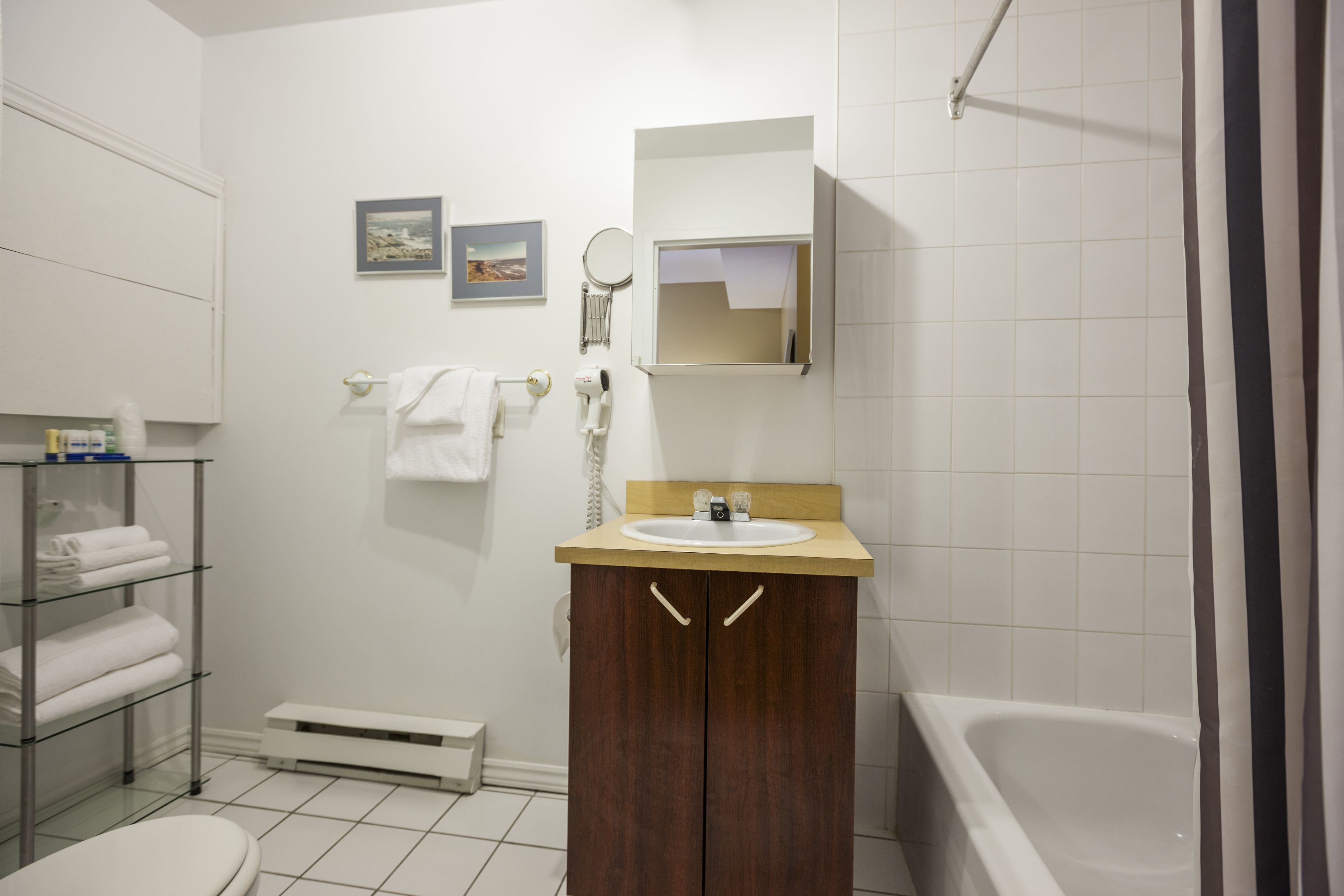 Un baño con lavamanos blanco, espejo, toallero y cortina de ducha.