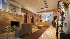 Een moderne woonkamer met een schouw van baksteen, een bank, een glazen salontafel met appels en een houten receptiebalie.
