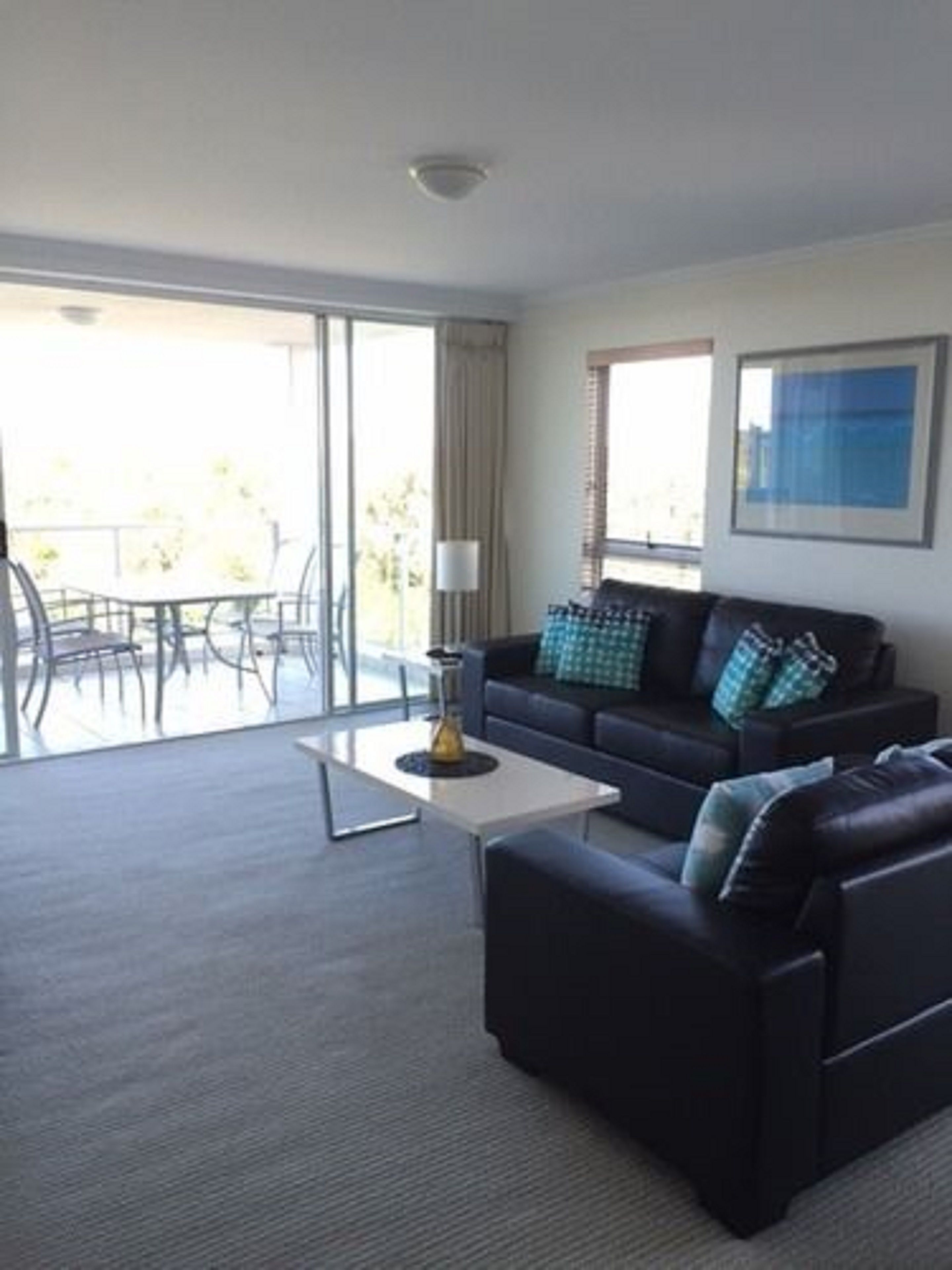 A modern living room with a sofa, coffee table, and a view of the outdoors.