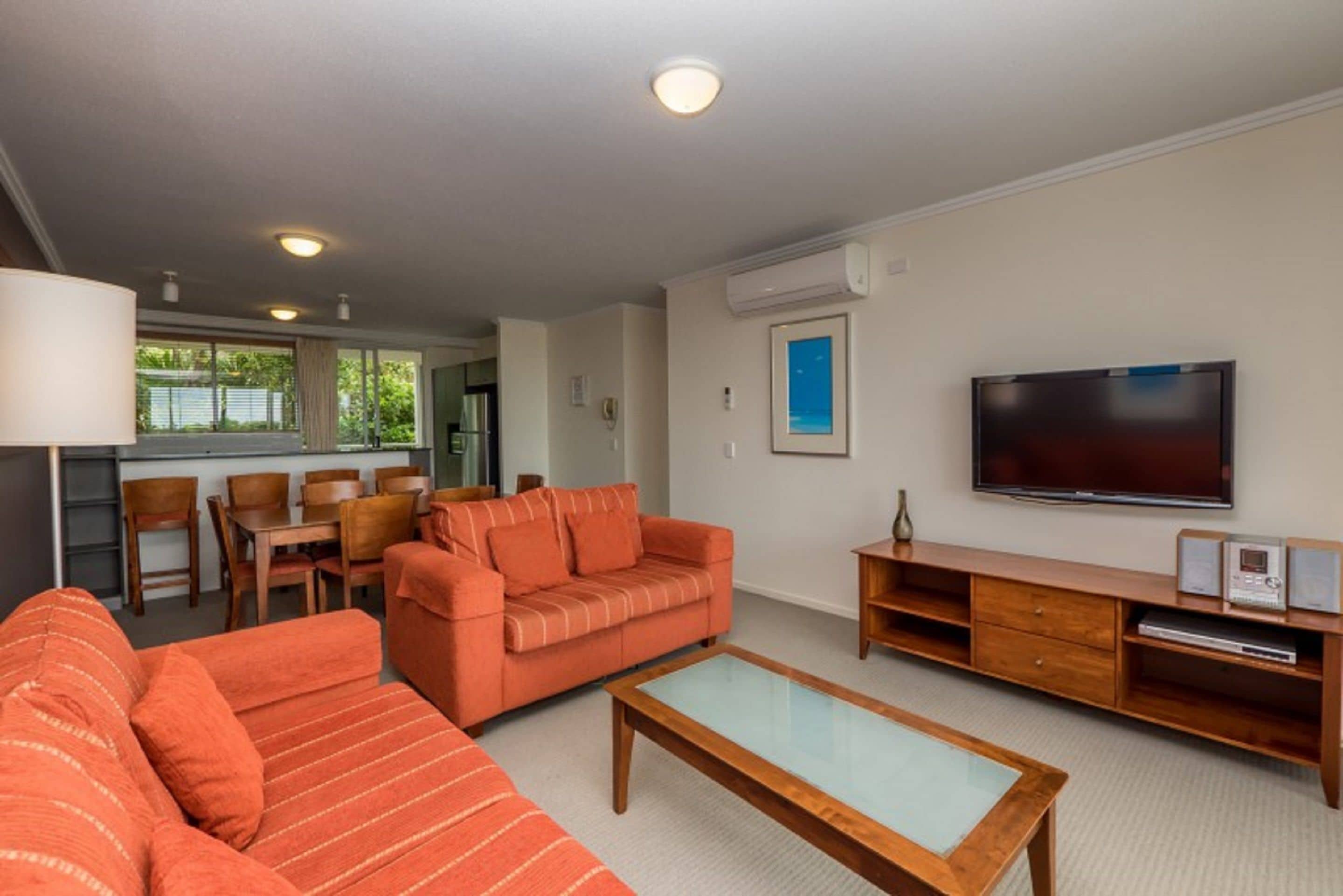 A living room with a sofa, coffee table, TV, and a dining area with chairs and a table.