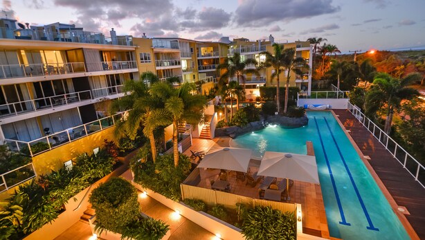 Un complexe hôtelier doté d’une piscine, de nombreux balcons et d’un aménagement paysager luxuriant.
