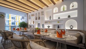 A modern interior with wicker furniture, a dining area, and built-in shelves with decorative items.