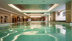 A large indoor swimming pool with a Harmony Pool Bar in the background.