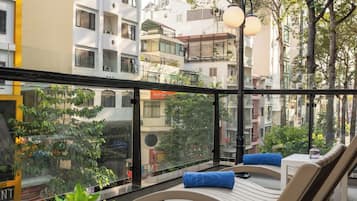 A rooftop terrace with seating areas, a view of the cityscape, and a glass railing.