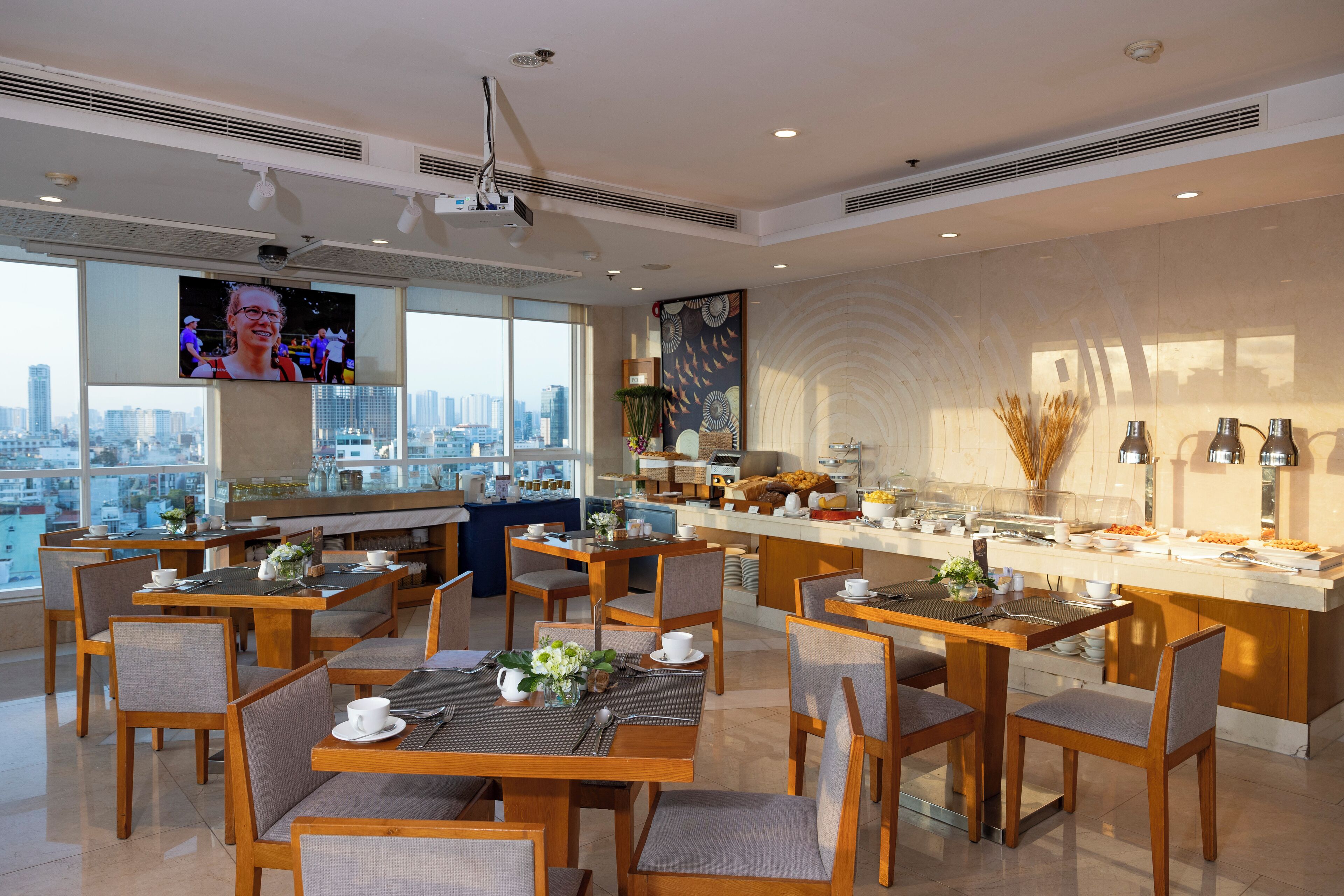 Ein moderner Essbereich mit mehreren Tischen und Stühlen, einer Buffettheke und einem großen Fenster mit Blick auf die Stadt.