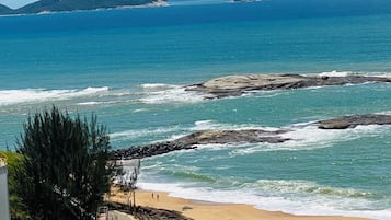 Vista costera con playa, costa rocosa e islas distantes.
