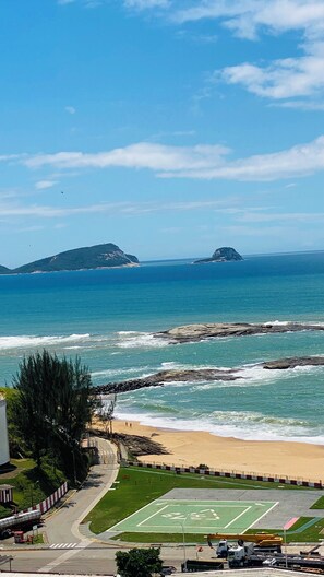 Une vue côtière comprenant une plage, une côte rocheuse et des îles au loin.