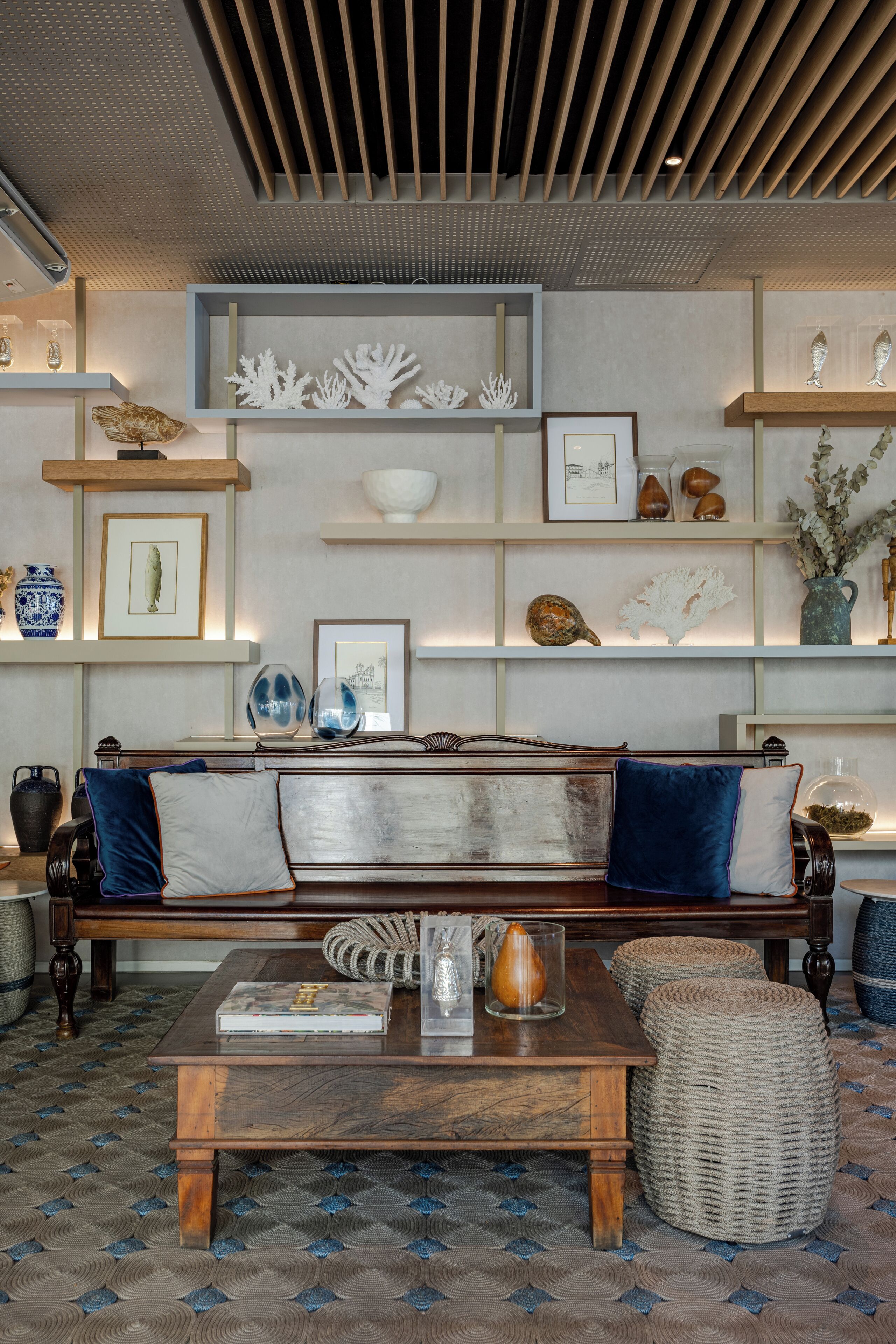 A cozy living room with a wooden bench, a coffee table, and shelves with decorative items.