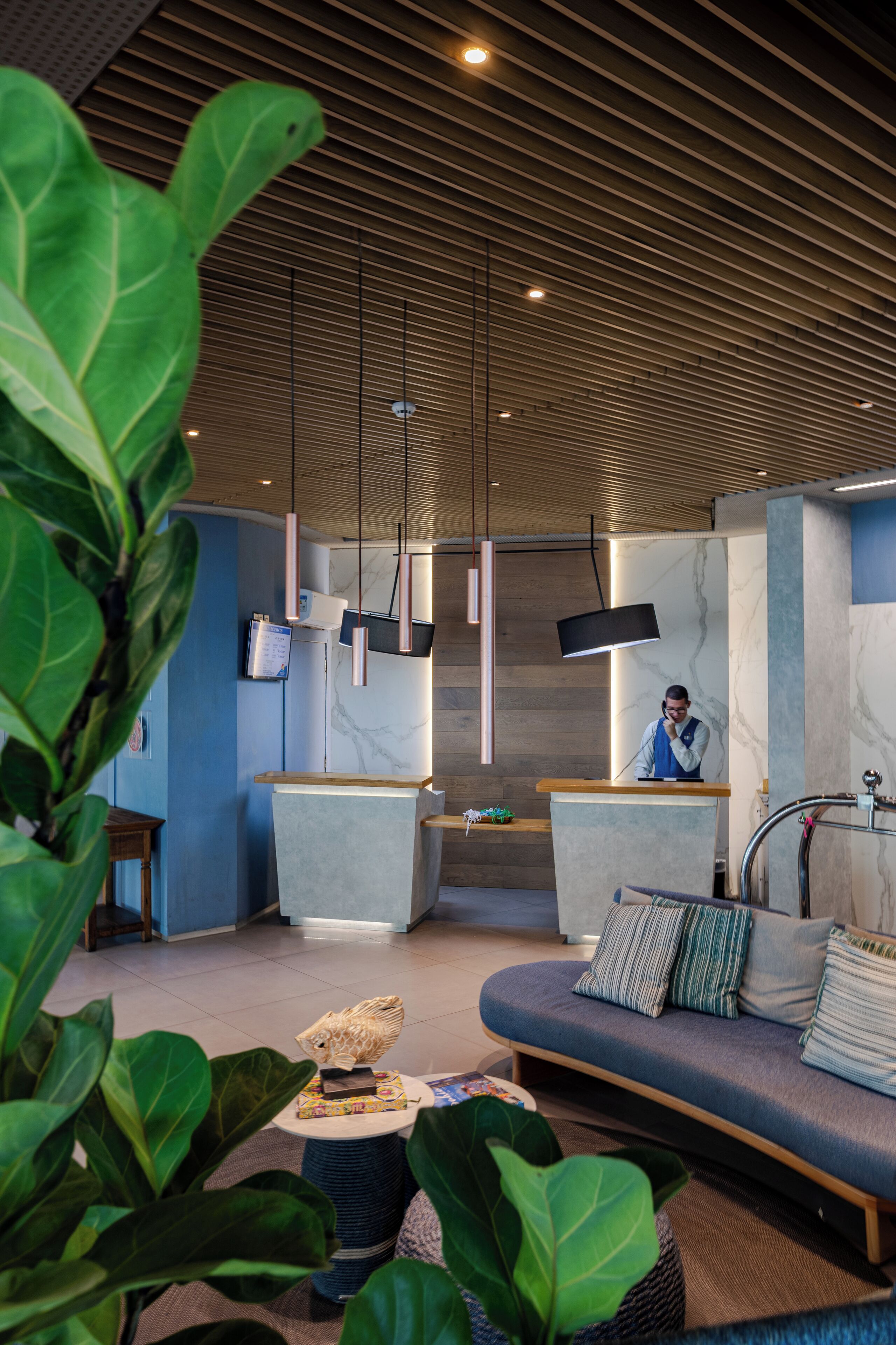 A modern lobby with a reception desk, seating area, and a staircase.