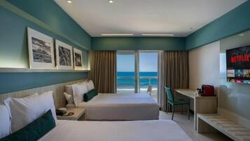 Een hotelkamer met een bed, een bureau en uitzicht op de oceaan.
