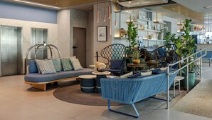 A modern lobby with a seating area, a staircase, and a bar area.